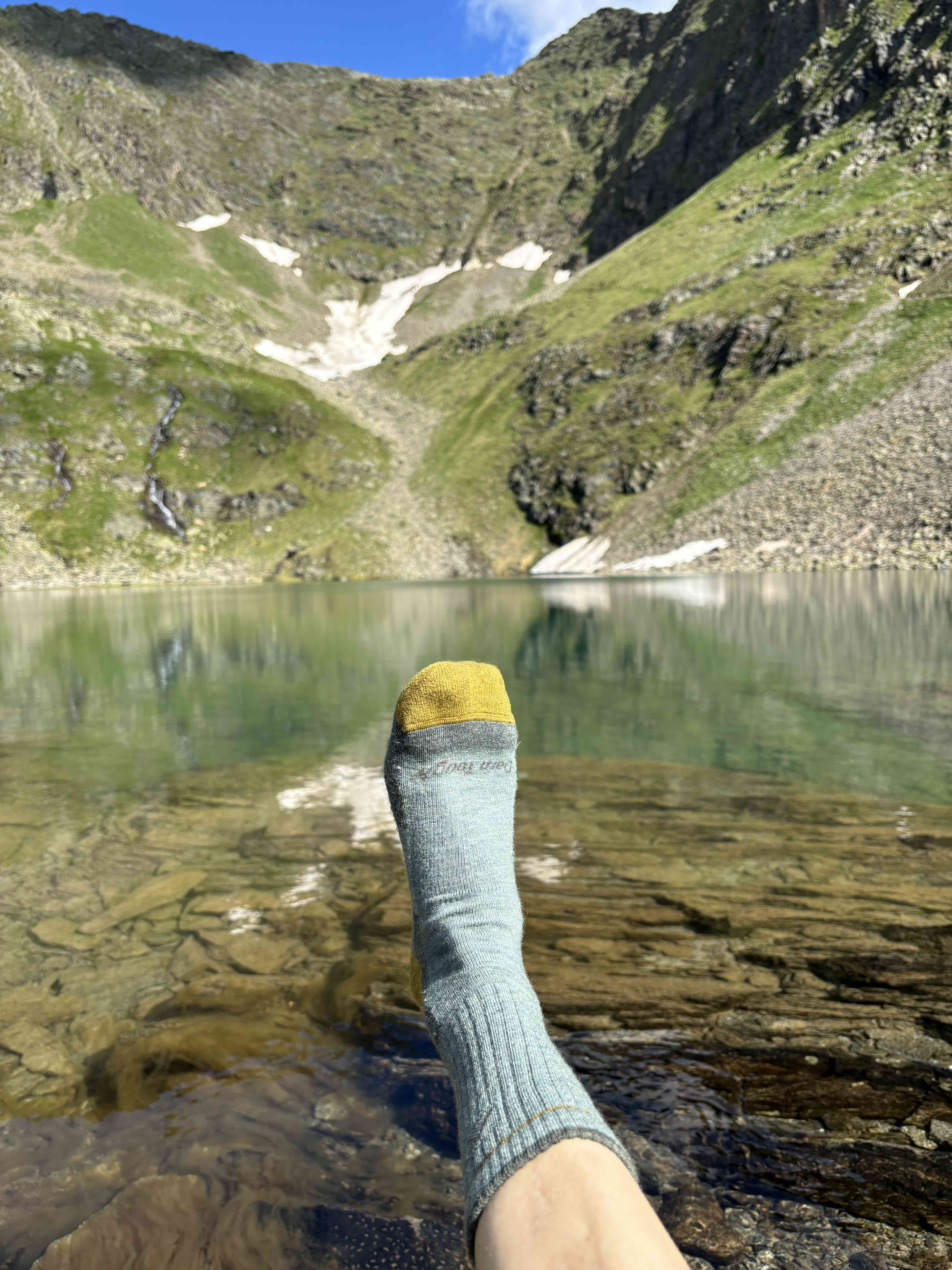 Socke am Fuß, See im Hintergrund