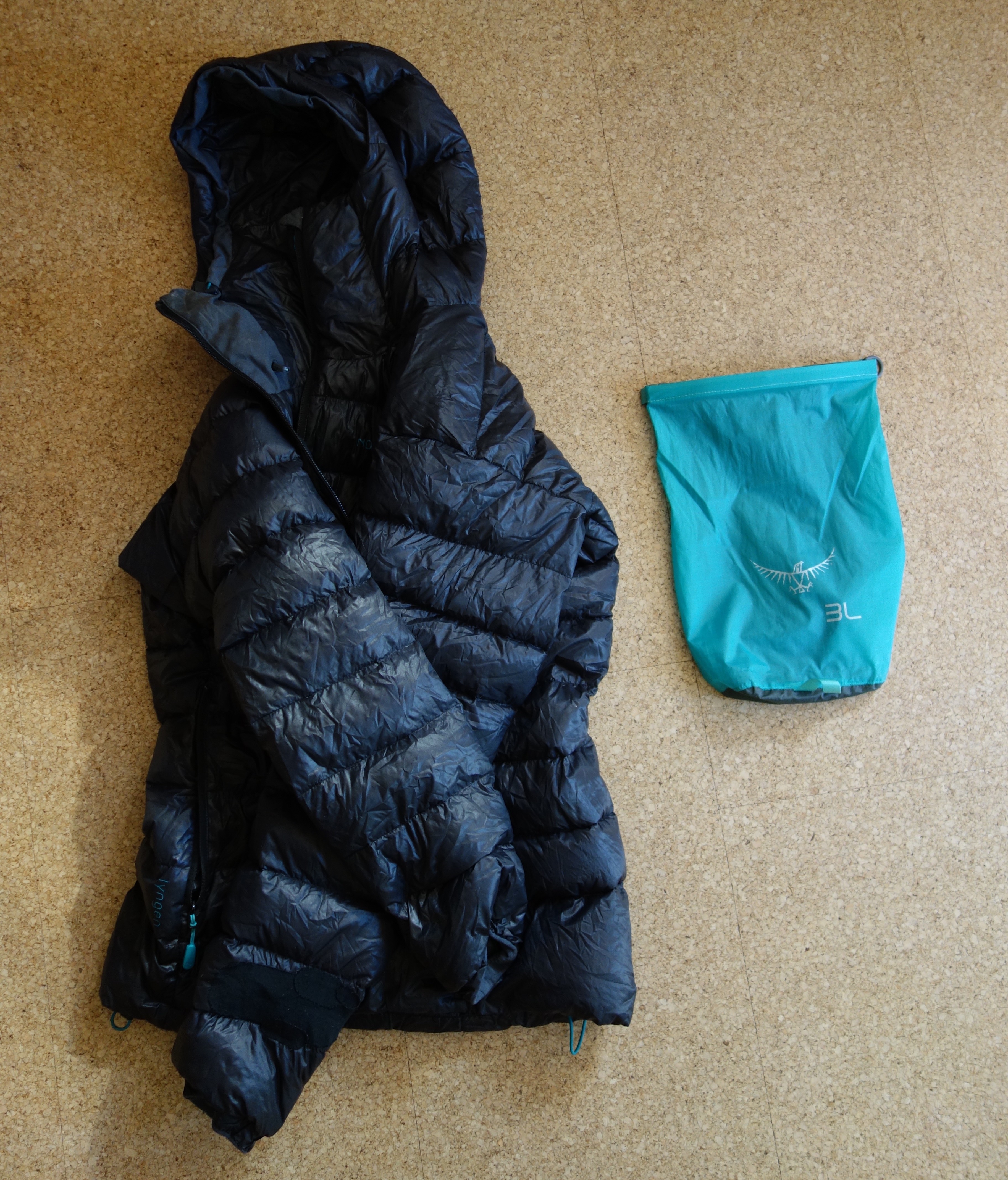In den Packsack wurde eine Daunenjacke gepackt. Beide liegen in diesem Bild nebeneinander.
