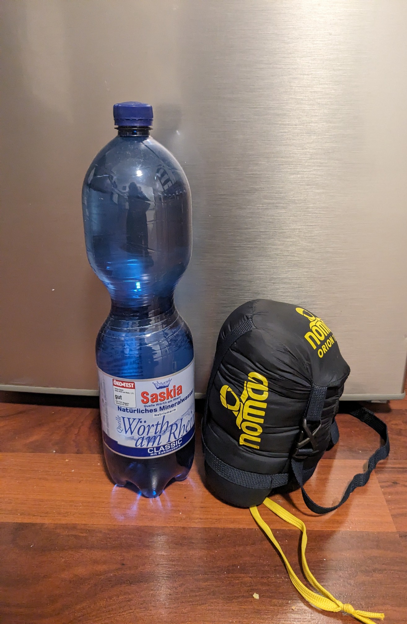 Der Schlafsacks steht komprimiert im Packsack neben einer 1.5l Flasche. Erst ist ungefähr halb so hoch