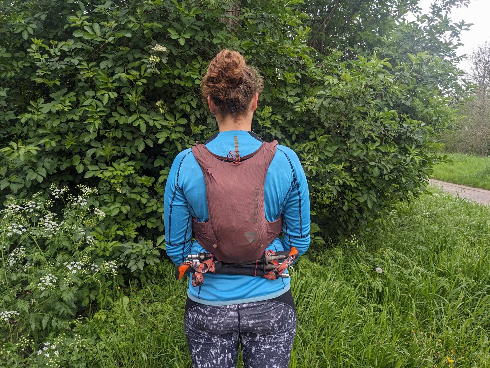 Man sieht den Rucksack auf dem Rücken einer Läuferin. All die Ausrüstung vom vorherigen Bild ist in der Laufweste. Sie sieht nicht übermäßig voll aus